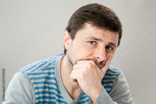 Fotografía Thoughtful handsome bearded man in a striped sweater leaning his head against hi