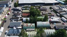 Aerial Bird View Of Old Rusty Metal Hangers Build Close Next To Each Other Located At Commercial Area The Buildings Have Different Colors Green Dark Red And Blue And Are Used As Workplaces 4k Quality