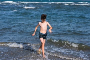 Wall Mural - Boy Jumping In Sea Waves with Water Splashes. Concept of summer vacation