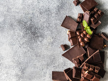 Various Chocolate Slices On A Grey Background Sprinkled With Mint Leafs