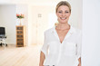 © Westend61 - Portrait of smiling woman wearing white blouse at home