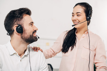 Close up of female manager putting hand on sholder of male coworker in headset in office