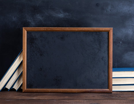 empty black chalk drawing frame and stack of books