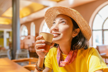 Wall Mural - Young woman drinking coffee or tea from paper cup in cafe