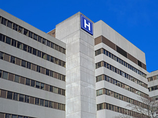 Large concrete building with  H sign for hospital