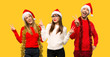 © luismolinero - A group of people Blonde woman dressed up for christmas holidays smiling and showing victory sign with both hands on yellow background