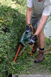 © WideAwake - Man in Motion Wielding Electric Shears to Prune a Long Hedge