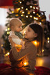 © natalialeb - Sisters near Christmas tree,eldest girl holds baby