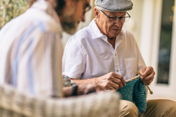 Wall Mural - Two old men sitting knitting warm clothes