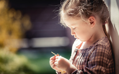 Baby girl with long hair and beautiful dress is considering a little doll