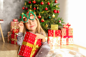 Portrait of cute happy five year old girl receiving many presents, Decorated Christmas tree with stack of wrapped gifts on background. Close up, copy space.