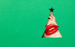 © Oleg Gekman - Beautiful Plump Bright Lips Of a Young Beautiful Woman with Red Lipstick Look Into the Pattern of Christmas Tree made of Colored Paper. Holiday Patterns. Tree. Green Paper