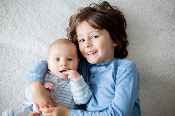 Sticker - Happy brothers, baby and preschool children, hugging at home on white blanket