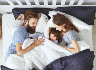 Wall Mural - happy family mother, father and child  in bed.