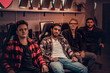© Fxquadro - A team of multiracial teenage gamers sitting on gamer chairs and looking at a camera in a gaming club or internet cafe.