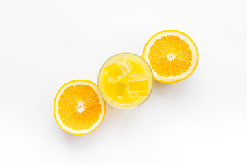 Canvas Print - Glass of cold orange juice near halfs of fresh oranges on white background top view pattern copy space