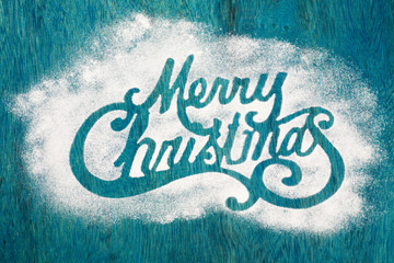 Merry Christmas sigh made out of sugar powder on blue background, flat lay