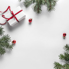 creative frame made of christmas fir branches on white paper background with red decoration, pine co