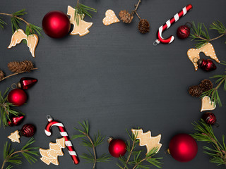 christmas background with frame with red baubles, green branches and other christmas items on blackboard