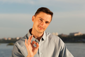 Wall Mural - portrait of a smiling young man. young brunette man rejoices, happy man, ok sign, pleasure and satisfaction
