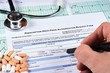 © Maksim Shchur - Human fill Prescription drugs prior authorization request form, pills, stethoscope on a EKG graph paper background. Close-up.