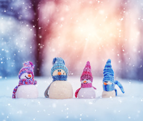 little knitted snowmans on soft snow on blue background