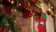 Man Hands Hanging Christmas Stocking Or Sock Above Fireplace Decorated With Colorful Flashing Garland Lights And Wreath. New Year Holidays Preparation And Decoration.
