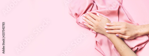 Foto Beautiful woman manicure on creative pink background with silk fabric