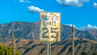 Old speed limit sign against mountain and sky