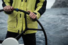  A Sailing Yacht Skipper Is At The Helm. Close-up. It's Cold, Waves.