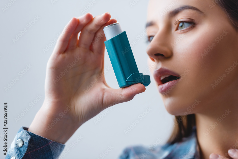 close-up view of young woman with asthma using inhaler - obrazy, fototapety, plakaty 