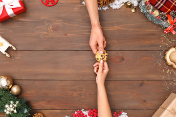 New Year. Man and woman holding cookie together isolated on decorated table top view close-up