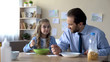 © motortion - Happy little girl and father eating cornflakes at breakfast, family traditions