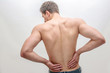 © estradaanton - Young man stand and hold hands on back. He feels pain in kidneys area. Isolated on white background.