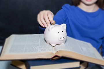 Teen puts coins in the piggy bank. The concept of paid education