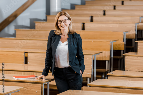 Fotografía beautiful female university professor smiling and looking at camera in classroom
