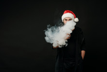 Man With Beard In Santa Red Hat Smoking Electronic Sigarette. Vape Pen. Vape Smoke. Christmas Concept