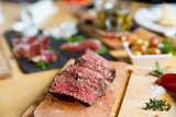 Fototapeta Łazienka - Juicy medium Beef Rib Eye steak slices in pan on Himalayan pink salt plates.