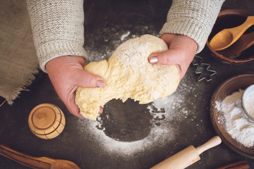 Process of making christmas cookies. Mature woman,  granny hands making dough.  Ingredients for baking pie: flour, pastry, crockery, kitchen utensils, fir tree cookie figure on dark background.