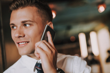 Wall Mural - Concept of success and well-being. Close up portrait of stylish smiling businessman talking by smartphone in restaurant interior