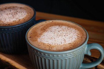 Close up view on coffee latte in blue cup on wooden background. Lifestyle toning. Copy space for text, logo or brand.