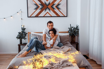 attractive cheerful man and woman on the bed hugging. couple cuddling 