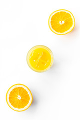 Canvas Print - Glass of cold orange juice near halfs of fresh oranges on white background top view pattern copy space