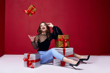Wall Mural - Beautiful young pretty woman with a bright evening make-up of shiny red lipstick on the lips brunette curly hair festive mood winter Christmas New Year St. Valentine's Day and birthday gift surprise.