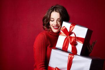 Wall Mural - Beautiful sexy young brunette girl with wavy hair bright evening make-up red lips long fluffy eyelashes hold gift box holiday New Year joy fun happy merry Christmas Eve party celebration.