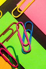 Paperclips on colorful different colour office stickers on black paper.