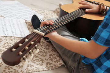 Poster - Little boy playing guitar on floor, closeup