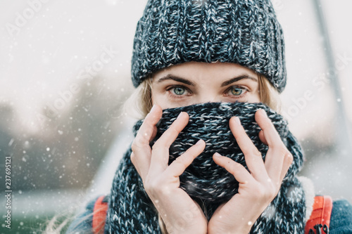 Fotomural portrait of young blonde woman closing face with winter scarf feeling cold under