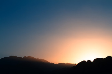Wall Mural - hiker watching sunset mountain with haze at hike in dusty air