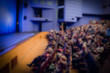Theatre stage. Blue curtain. Defocused image, bokeh effect. People in the auditorium of the theater or concert hall.